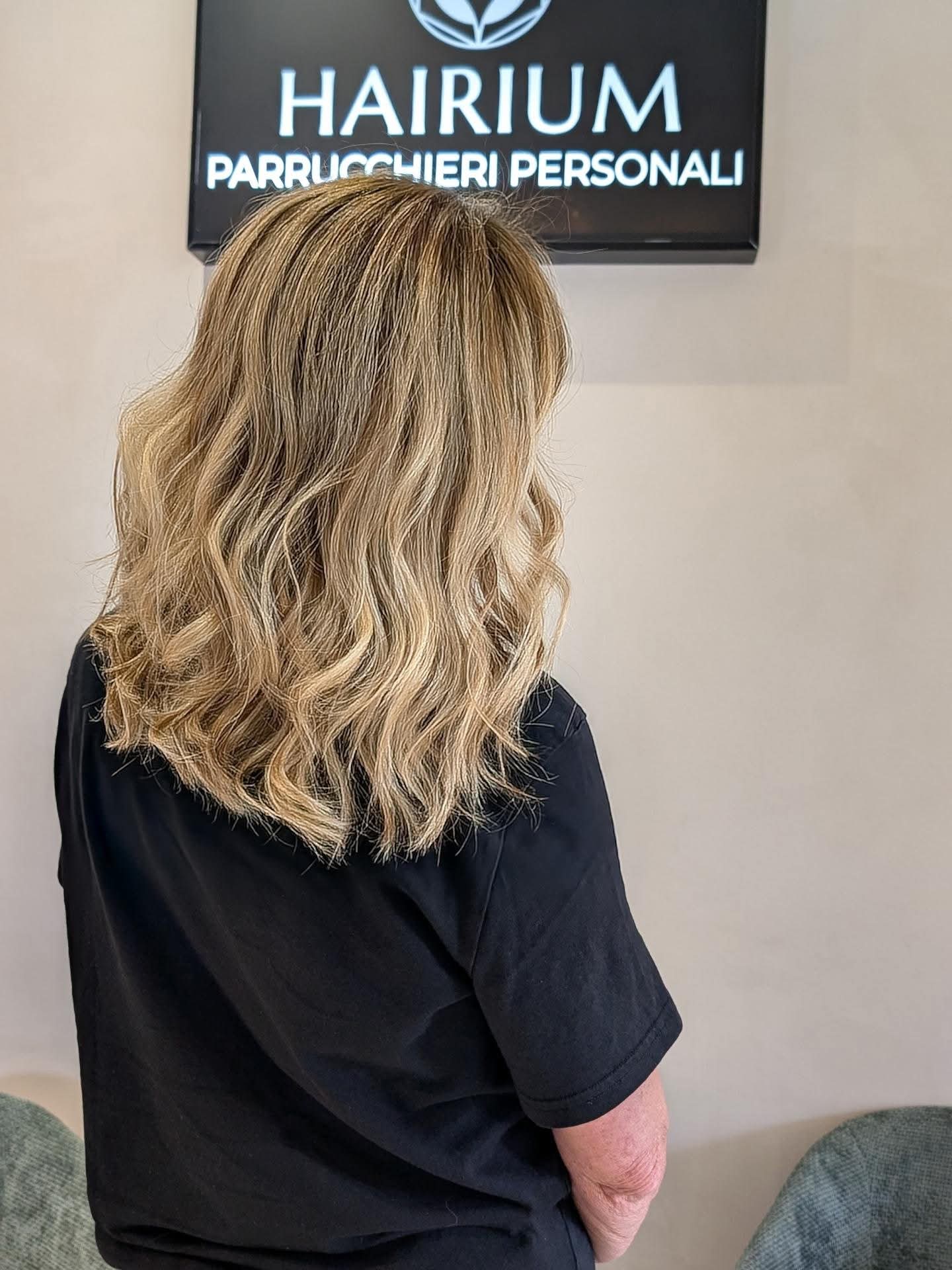 Schiaritura bionda con onde morbide sotto l'insegna Hairium Parrucchieri Personali