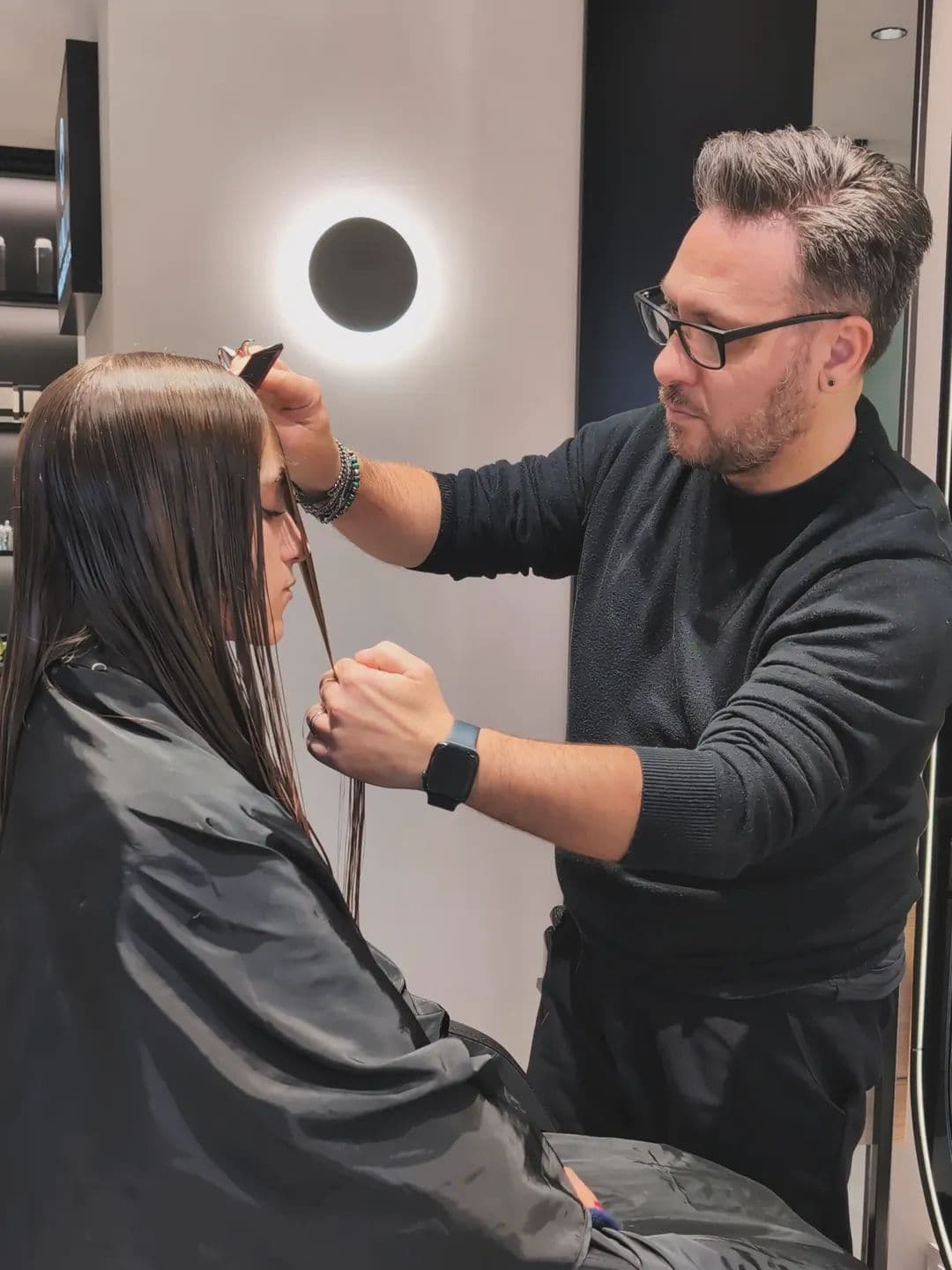 Un hair stylist di Hairium taglia la frangia a una cliente con i capelli bagnati